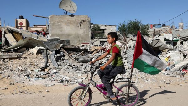 A Palestinian child rides his bicycle in front of the ruins of a building destroyed during recent Israeli bombing in Rafah, in the southern Gaza Strip, on May 26, 2021. Diplomatic efforts are underway to solidify a fragile Egypt-brokered truce that halted the fighting, with plans to rebuild the Gaza Strip where Israeli air strikes damaged infrastructure and levelled buildings