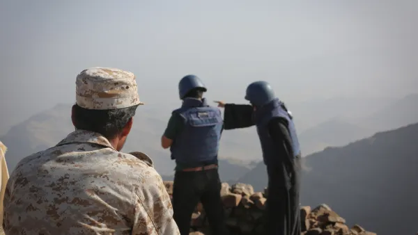 A Yemeni soldier looks at two journalists reporting the event 