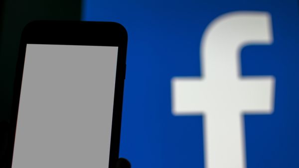 blank smartphone display and blurred Facebook logo