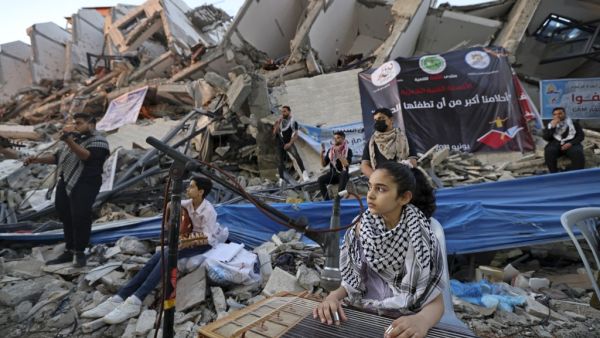 Palestinian musicians perform on the rubble of the Hanadi Tower during an event organised by the Palestinian Committee on Youth and Culture in Gaza City on June 2, 2021, more than a week after a ceasefire brought an end to 11 days of hostilities between Israel and Gaza rulers Hamas