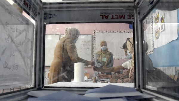 A woman signs a voter registry after casting her ballot at a polling station in Bouchaoui, on the western outskirts of Algeria's capital Algiers, on June 12, 2021 during the 2021 parliamentary elections. Polls opened in Algeria for a parliamentary election overshadowed by a crackdown on a long-running protest movement that has campaigned for a mass boycott. Pro-government parties have urged a big turnout for the "crucial vote" which they hope will restore stability after two years of turmoil since the force