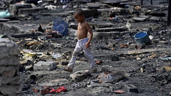 A young Rohingya refugee looks for his belongings amid the charred remains of his camp following a fire incident that broke out earlier today in New Delhi on June 13, 2021.  Money SHARMA / AFP UN data collected on Rohingya Muslim refugees in Bangladesh was shared with Myanmar