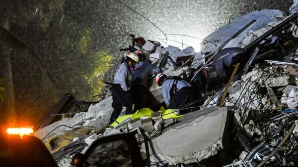 Search and Rescue personnel pull a body out of the rubble after the partial collapse of the Champlain Towers South in Surfside, north of Miami Beach, on June 24, 2021. CHANDAN KHANNA / AFP Building collapsed after midnight near Miami Beach, according to officials.