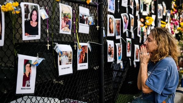 A woman prays in front of photos at the makeshift memorial for the victims of the building collapse, near the site of the accident in Surfside, Florida, north of Miami Beach on June 27, 2021. CHANDAN KHANNA / AFP Miami building collapsed 3 days ago leaving 9 killed so far.