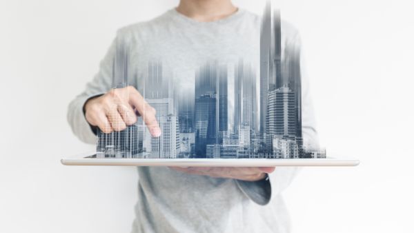 a man using digital tablet, and modern buildings hologram