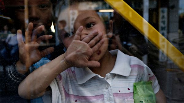 Migrants and refugees wait to be transported to the new state-run facilities 