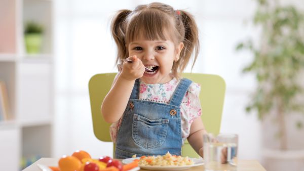 Cute child little girl eating healthy food in kindergarten
