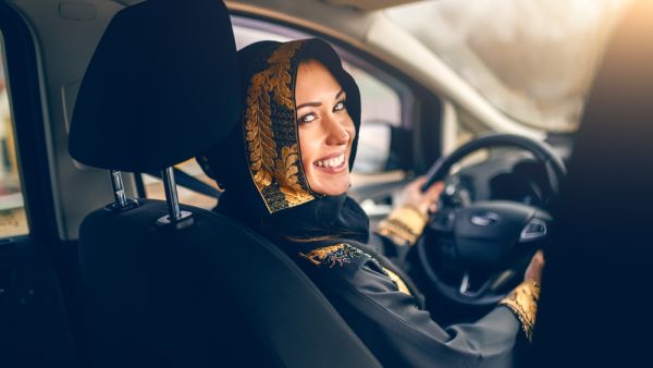 Beautiful arabian woman driving a car looking at camera.