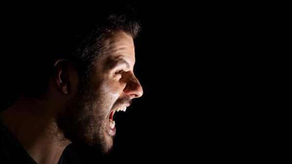 Angry man shouting out loud isolated on black background.