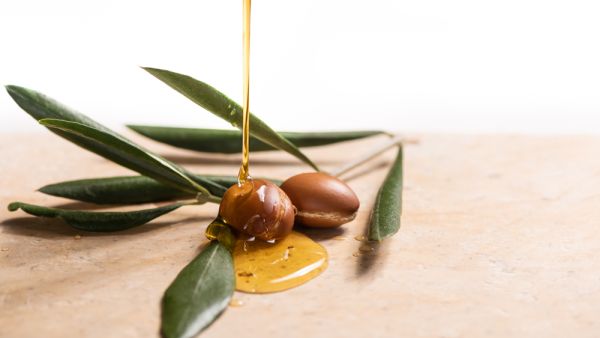 Argan oil, used for cosmetics, pouring over two argan seeds on a stone table.