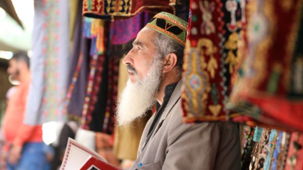 An old man, white hair, works in the market in and reads a book. Palestine, Hebron