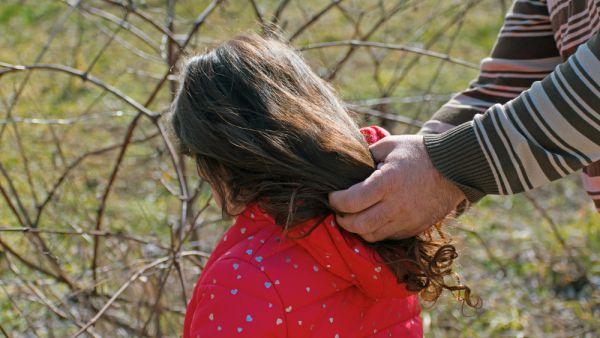 Man's hands on the hair of a little girl