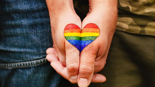 Rainbow heart drawing on hands, LGBTQ love symbol