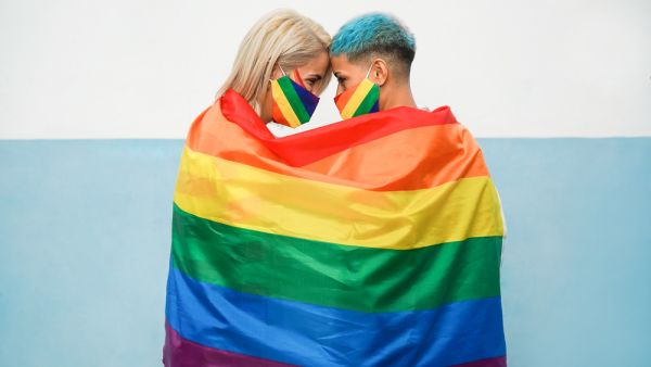 Young couple of women hugging under rainbow flag