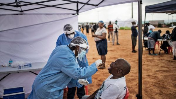 A healthcare worker collecting a swab for a COVID-19 test from a community member. AFP via Getty Images