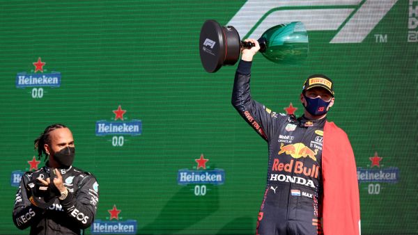 Red Bull's Dutch driver Max Verstappen (R) holds the winner's trophy as Mercedes' British driver Lewis Hamilton (L) applauds on the podium of the Zandvoort circuit after the Netherlands' Formula One Grand Prix in Zandvoort on September 5, 2021. (Photo: AFP)