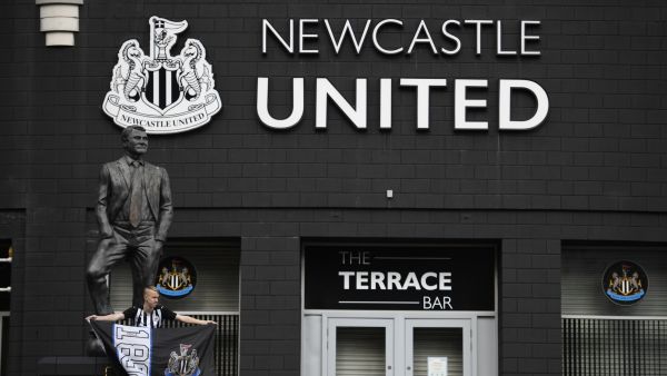 A Newcastle United supporter is seen posing in front of the statue of the late former manager Bobby Robson outside the club's stadium St James' Park in Newcastle upon Tyne in northeast England on October 8, 2021, after the sale of the football club to a Saudi-led consortium was confirmed the previous day. (Photo by Oli SCARFF / AFP)