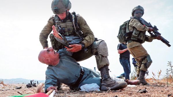 Israeli soldiers hold a Palestinian protester 