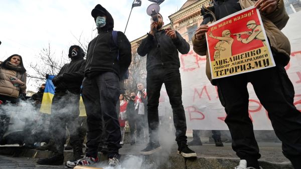 Ukrainian nationalists holding placards and burning smoke flares participate in a protest action outside the Belarusian embassy in Kiev on November 10, 2021, to support Poland in a migrant crisis unfolding on the Belarusian-Polish border. (Photo by Sergei SUPINSKY / AFP) migrant crisis increases near the Belarusian-Polish border