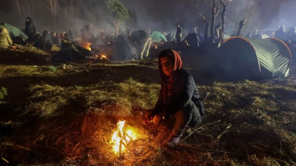 Migrants aiming to cross into Poland camp near the Bruzgi-Kuznica border crossing on the Belarusian-Polish border on November 17, 2021. (Photo by Maxim GUCHEK / BELTA / AFP)  migrants at Belarus-Poland border