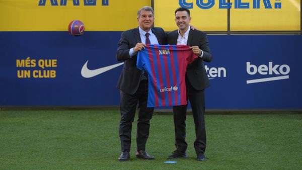 Newly-appointed FC Barcelona's Spanish coach Xavi Hernandez (R), flanked by FC Barcelona's Spanish president Joan Laporta, poses with his jersey during the presentation ceremony at the Camp Nou stadium in Barcelona on November 8, 2021. (Photo by LLUIS GENE / AFP)