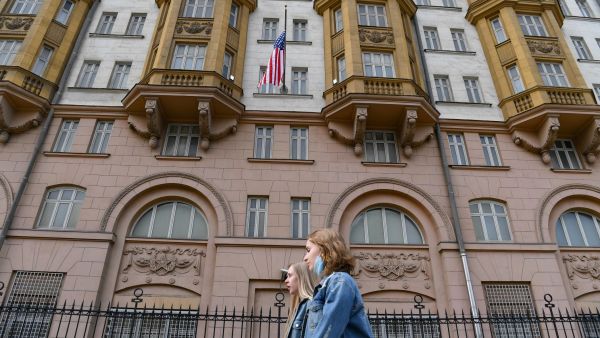 Two young women walk past the US embassy building in Moscow on April 15, 2021. Russia orders longtime US Embassy staff to leave country by Jan. 31