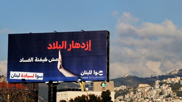 This picture taken on November 26, 2021 shows an anti-corruption billboard with the Arabic slogan "the country flourishing not corruption dominating" on display on the side of a highway in Lebanon's coastal city of Jounieh, north of the capital. . (Photo by JOSEPH EID / AFP) The national dialogue aims to end disruption of Cabinet meetings