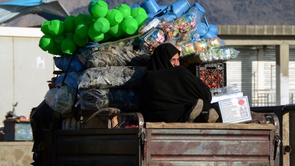 A burqa clad Afghan woman travels on a vehicle carrying vegetables and plastic containers in Kandahar on February 14, 2022. (Photo by Javed TANVEER / AFP) Summit aims to response to the growing humanitarian crisis in Afghanistan.