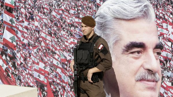 A member of the Lebanese security forces stands guard in front of a billboard bearing a portrait of slain former Lebanese prime minister Rafik Hariri during a ceremony to mark the tenth anniversary of his assassination on February 14, 2015, in downtown Beirut. AFP PHOTO / ANWAR AMRO Lebanese prime minister Rafik Hariri