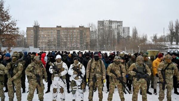 Military instructors and civilians stand prior to a training session at an abandoned factory in the Ukrainian capital of Kyiv, on January 30, 2022. (Sergei SUPINSKY / AFP) Soldiers for the Ukraine war