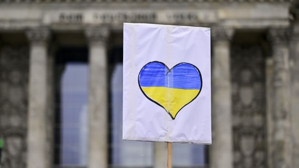 A supporter of the Fridays for Future movement holds a sign with a heart-shaped Ukrainian flag in front of the Reichstag building during a demonstration against the war in Ukraine on March 3, 2022 in Berlin. (Photo by John MACDOUGALL / AFP) Second round of talks to start Today