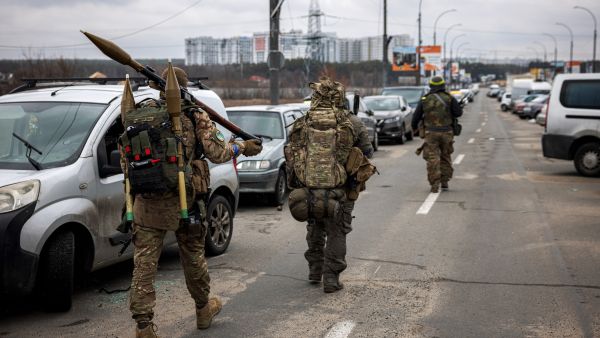 Ukrainian servicemen carry rocket-propelled grenades and sniper rifles as they walk towards the city of Irpin, northwest of Kyiv, on March 13, 2022. At least two dead in strike on residential building in Kyiv, Ukraine