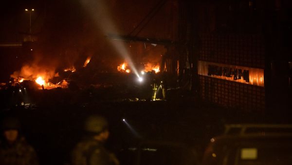 Ukrainian police officers stand near a warehouse that was hit by the debris of a downed rocket in Kyiv on March 20, 2022 (Photo by FADEL SENNA / AFP) shopping centre in the Ukrainian capital Kyiv was destroyed by Russian airstrikes.