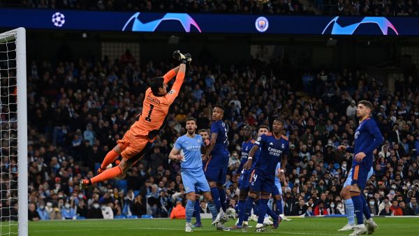 Real Madrid's Belgian goalkeeper Thibaut Courtois jumps to stop the ball during the UEFA Champions League semi-final first leg football match between Manchester City and Real Madrid, at the Etihad Stadium, in Manchester, on April 26, 2022. (Photo by Paul ELLIS / AFP)