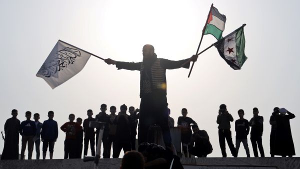 A Syrian man waves flags during celebrations for Eid al-Fitr, the Muslim holiday which starts at the conclusion of the holy fasting month of Ramadan, in front of the Grand Mosque in Syria's rebel-held northwestern city of Idlib, on May 2, 2022. (Photo by Mohammed AL-RIFAI / AFP) War crimes