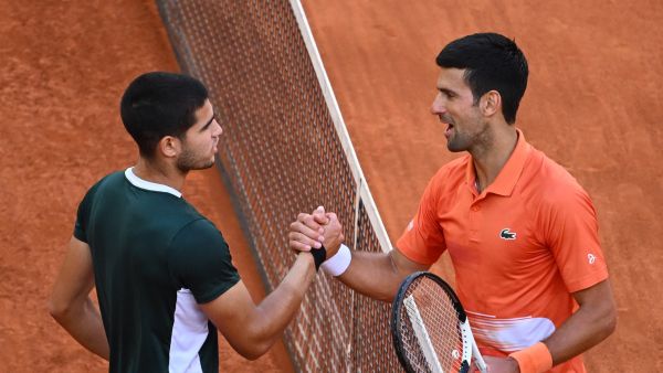 Spain's Carlos Alcaraz (L) and Serbia's Novak Djokovic shake hands at the end of their 2022 ATP Tour Madrid Open tennis tournament men's singles semi-final match at the Caja Magica in Madrid on May 7, 2022. (Photo by GABRIEL BOUYS / AFP)