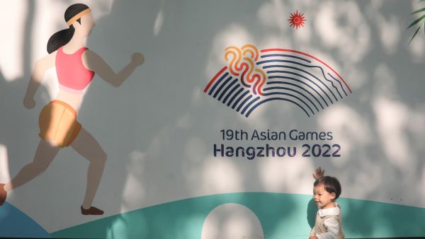 A child plays in front of a wall with images of the 2022 Asian Games in Hangzhou, in China's eastern Zhejiang province on May 8, 2022. China's ambitions to be a global sporting hub took a heavy blow as the May 6, 2022 postponement of this year's Asian Games further isolated a country already cut off by its hardline zero-Covid strategy. (Photo by AFP) / CHINA OUT