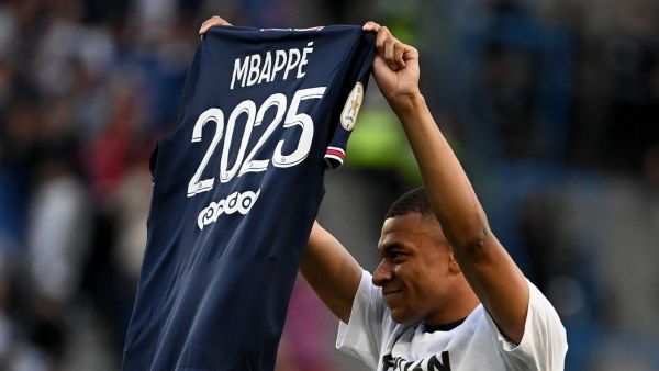 Paris Saint-Germain's French forward Kylian Mbappe poses with a jersey after the announcement he staying at PSG until 2025 before the French L1 football match between Paris Saint-Germain (PSG) and Metz at the Parc des Princes stadium in Paris on May 21, 2022. (Photo by Anne-Christine POUJOULAT / AFP)