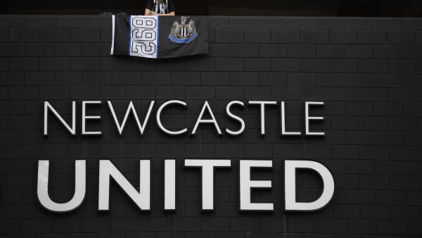 A Newcastle United football club supporter stands with a flag above the club logo at their stadium St James' Park in Newcastle upon Tyne in northeast England on October 8, 2021. (Photo by Oli SCARFF / AFP)