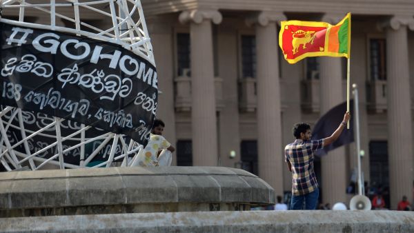 A man waves Sri Lanka's national flag outside presidential secretariat in Colombo on July 13, 2022. Sri Lanka is mired in a deep political and economic crisis, and on July 13, the country's president flew out of the country days after a huge crowd of protesters stormed his residence. (Photo by Arun SANKAR / AFP) Sri Lanka