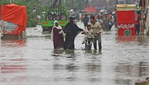 People wade across a flooded street in Karachi 
