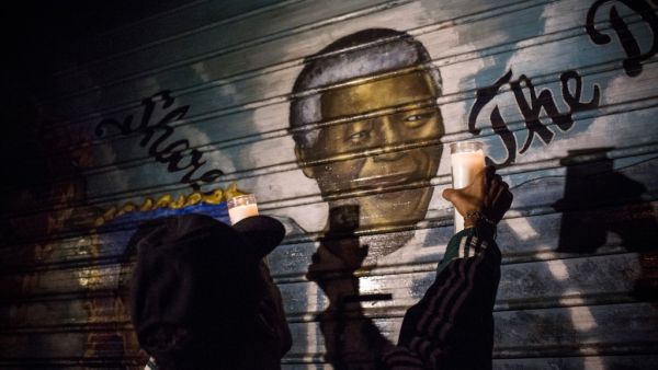 A man holds up candles to a mural depicting former South African President and civil rights champion Nelson Mandela, who died today, on December 5, 2013 in the Harlem neighborhood of the Manhattan borough of New York, United States. Andrew Burton/Getty Images/AFP  Nelson Mandela
