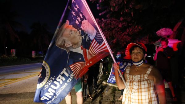 Supporters of former President Donald Trump hold flags in front of his home at Mar-A-Lago on August 8, 2022 in Palm Beach, Florida. The FBI raided the home to retrieve classified White House documents. Eva Marie Uzcategui/Getty Images/AFP Mar-a-Lago