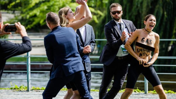 Topless demonstrators with the slogan on their skin reading "GAS EMBARGO NOW" protest as the security personnel tries to take them away from the German Chancellor Olaf Scholz during the Federal Government's Open Day event at the Chancellery in Berlin on August 22, 2022. (Photo by JENS SCHLUETER / AFP) Topless women