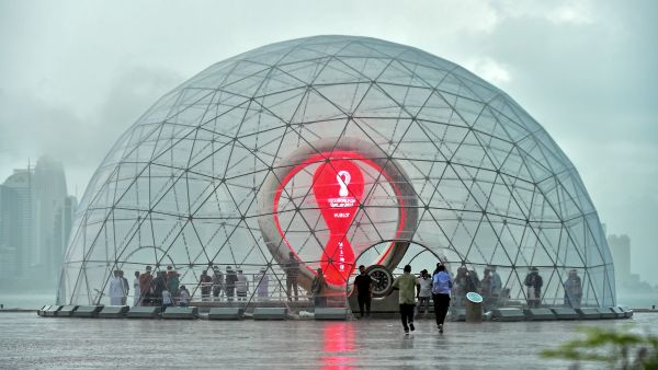 People take cover inside the FIFA World Cup Qatar 2022 countdown clock during heavy rains in the Qatari capital Doha on July 28, 2022. (Photo by AFP)