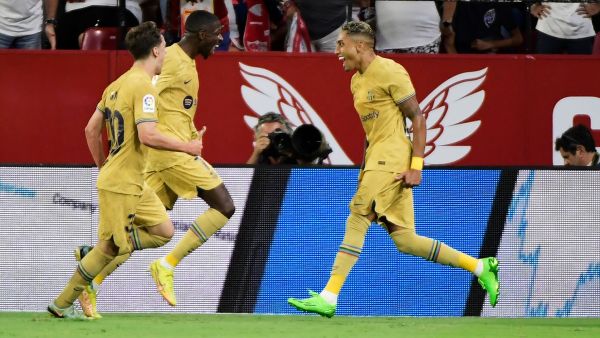 Barcelona's Brazilian forward Raphinha (R) celebrates with teammates after scoring his team's first goal during the Spanish league football match between Sevilla FC and FC Barcelona at the Ramon Sanchez Pizjuan stadium in Seville, on September 2, 2022. (Photo by CRISTINA QUICLER / AFP)