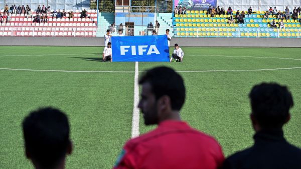 Youths hold a banner with the FIFA emblem before the start of a football match between Shaheen Asmayee and the Abasin Sape during the Amn Tournament, which includes six Afghan Premier League clubs, at Afghanistan Football Federation Stadium in Kabul on November 5, 2021. (Photo by Hector RETAMAL / AFP)