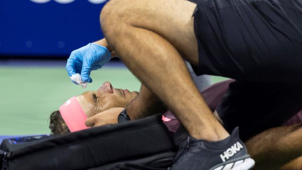 Spain's Rafael Nadal lies on the court and receives medical attention after hitting himself in the face with his racket during his 2022 US Open Tennis tournament men's singles second round match against Italy's Fabio Fognini at the USTA Billie Jean King National Tennis Center in New York, on September 1, 2022. (Photo by COREY SIPKIN / AFP)