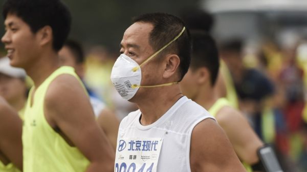 A runner wears a face mask as he takes part in the 35th Beijing International Marathon in Beijing on September 20, 2015, with the 42-kilometer course beginning at Tiananmen Square and ending at the Olympic Park. Some participants wore face masks to protect themselves from air pollution. AFP PHOTO / FRED DUFOUR (Photo by FRED DUFOUR / AFP)