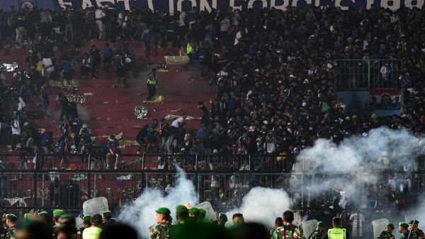 This picture taken on October 1, 2022 shows security personnel (lower) on the pitch after a football match between Arema FC and Persebaya Surabaya at Kanjuruhan stadium in Malang, East Java. At least 127 people died at a football stadium in Indonesia late on October 1 when fans invaded the pitch and police responded with tear gas, triggering a stampede, officials said. (Photo by AFP)
